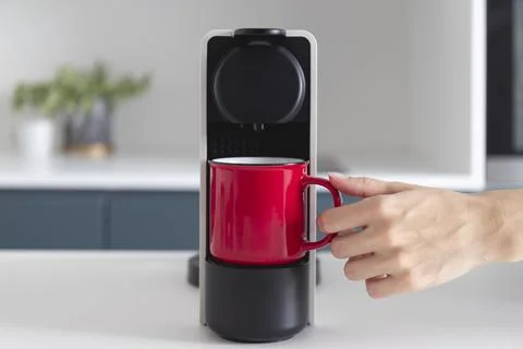 Capsule coffee machine and espresso in red cup. Breakfast time Stock Photos