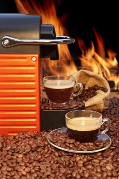 Capsule coffee machine with two espresso cups near fireplace Stock Photos