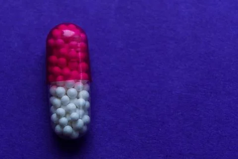 Capsule with granules on blue background Stock Photos