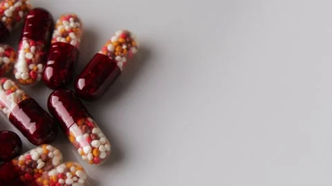 A capsule with multi-colored granules is rolling to pills Видео 274503073