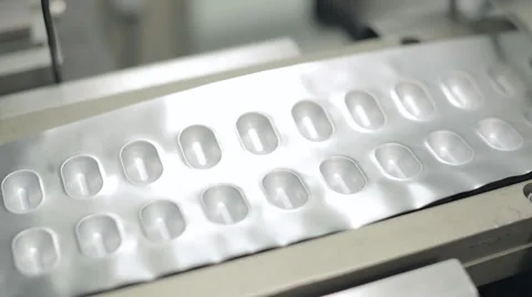 Capsule Packaging Moving through a Pressing Machine Stock Footage 68642995