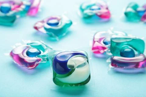 Capsule for washing on blue background. Spring clothes cleaning. Stock Photos