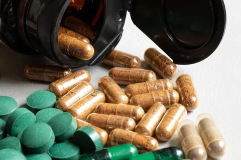 Capsules and green tablets on a light background and a jar, related to medici Stock Photos