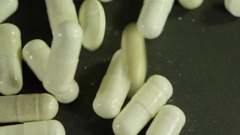 Capsules and Pills Piled on Black Surface 動画素材 345425307