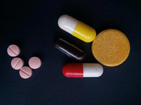 Capsules and tablets on black background. Stock Photos
