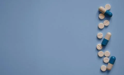 Capsules and tablets on a blue background on the right, a photo for a medic.. Stock Photos