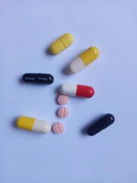 Capsules and tablets on white background, red, yellow, black and pink color. Stock Photos