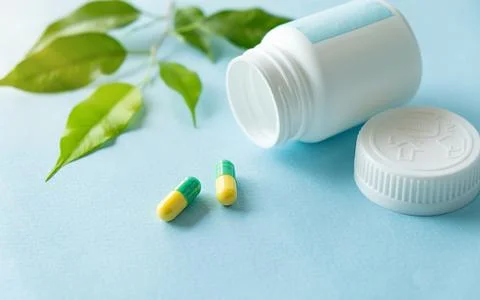 Capsules green in an open jar with leaf some tablets are on the table Stock Photos