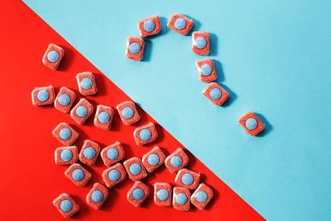 Capsules for kitchen dishwashers and a question mark on a blue and red backgr Foto stock