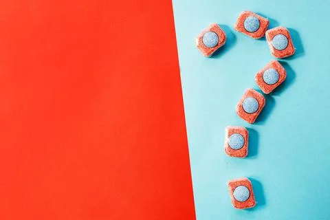 Capsules for kitchen dishwashers and a question mark on a blue and red backgr Foto stock