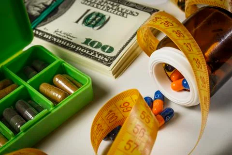 Capsules poured from a jar, a pack of dollars and a centimeter on the table a Stock Photos