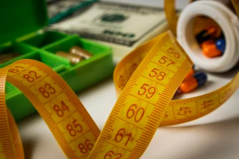Capsules poured from a jar, a pack of dollars and a centimeter on the table a Stock Photos