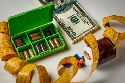 Capsules poured from a jar, a pack of dollars and a centimeter on the table a Stock Photos