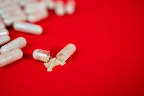 Capsules scattered on red surface, pharmaceutical background Stock Photos