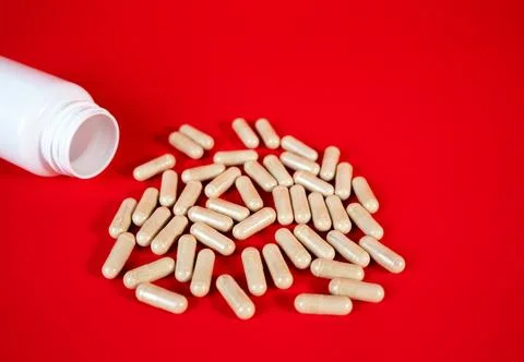Capsules spilling from bottle on red background Stock Photos