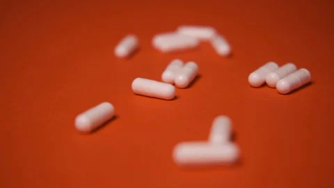Capsules, white tablets lie, roll on a red table, background, medicine, virus Stock Footage 125351642