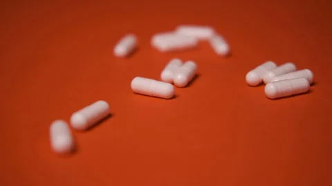 Capsules, white tablets lie, roll on a red table, background, medicine, virus Stock Footage 125351649