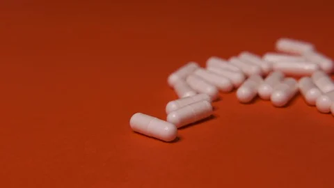 Capsules, white tablets lie, roll on a red table, background, medicine, virus Stock Footage 125351682