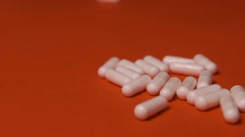 Capsules, white tablets lie, roll on a red table, background, medicine, virus Stock Footage 125351707