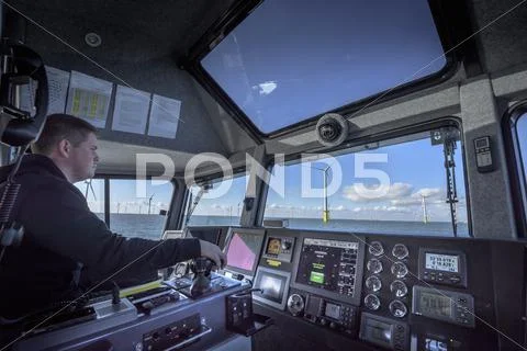 Captain Of Boat Steering Through Offshore Wind Farm