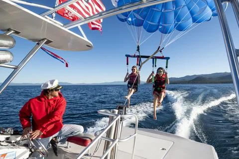 The captain smiles as he sends off two women in to the air while they parasai Фото