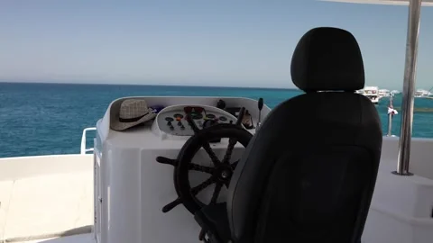 Captain’s chair faces endless blue sea calm marina ahead straw hat on the dashbo Stock Footage 310818898