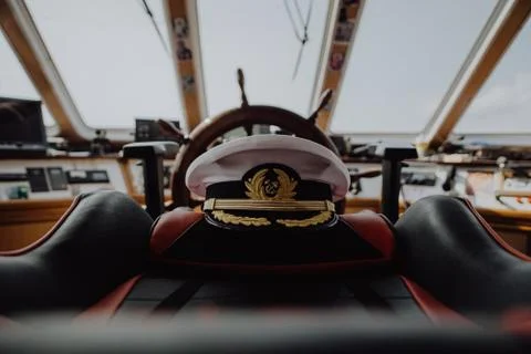 Captains hat left on the captains char on an old ship Stock Photos