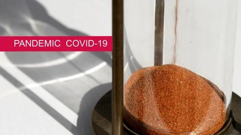 Caption "Pandemic Covid 19" on red background with sand hour glass 動画素材 126788161