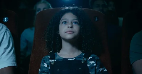 Captivated little girl in a movie theatre is awestruck by a incredible moment on Stock Footage