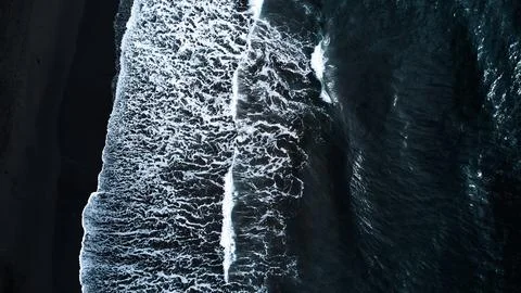 A captivating Aerial View of Waves forcefully Crashing on a stunning Black Sand Stock Photos
