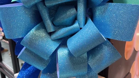 Captivating blue glitter gift bow slowly rotating for a festive ambiance Stock Footage 292320058