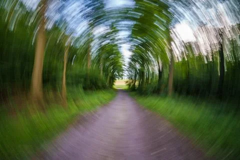 A captivating, blurred pathway surrounded by lush green trees, evoking a sens Stock Photos