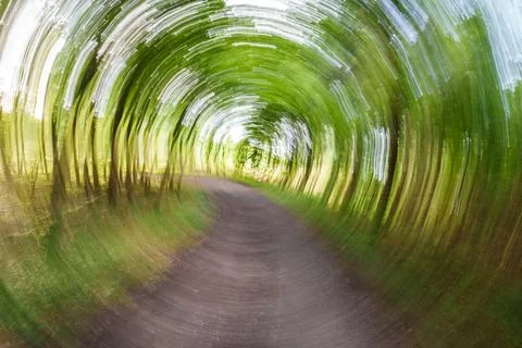 A captivating, blurred pathway surrounded by lush green trees, evoking a sens Stock Photos