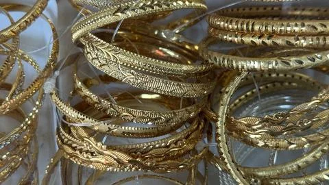 A captivating close up of multiple golden bangles stacked, each adorned with  스톡 사진