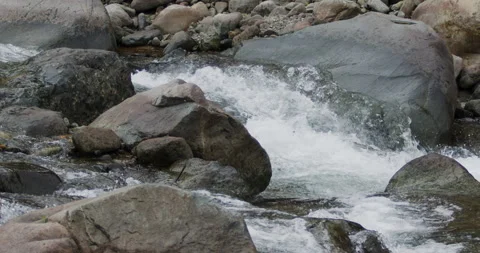 Captivating Close-Up: Slow-Motion Flow of River Current Through Stunning Rocks Stock Footage 240952846