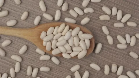 A captivating close up view of dry cannellini beans on a rustic wooden tabl.. Video stock 337404894