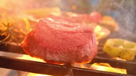 A captivating close up view of a raw beef steak being placed on a flaming hot Stock Footage 340952284