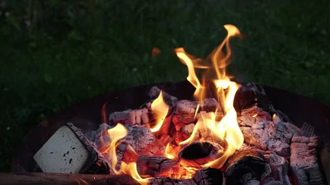 Captivating flames dance in the night as embers glow around the fire pit Stock Footage 317959968