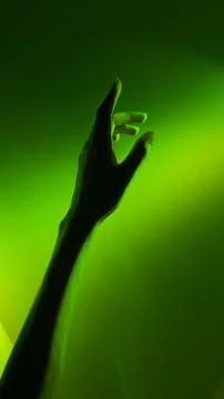 A Captivating Glimpse of a Hand Reaching Out Against a Green-Illuminated Stock Photos