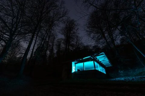 A captivating night scene featuring a rustic wooden cabin bathed in an otherw Stock Photos
