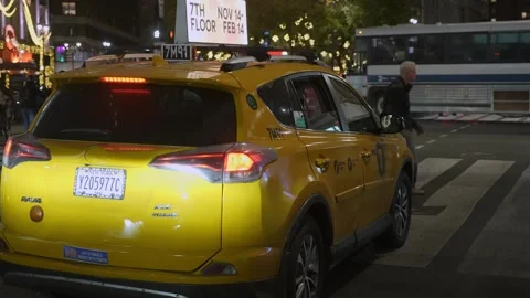 A captivating nighttime scene featuring a vibrant yellow taxi within a bustling Vidéo 295076840