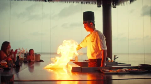 A captivating teppanyaki chef performs a stunning fire show for guests Stock Footage 319768101