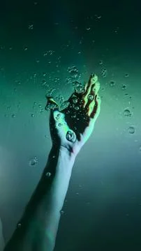 A Captivating Underwater Visual of a Hand Reaching Up Through Bubbles in a Stock Photos