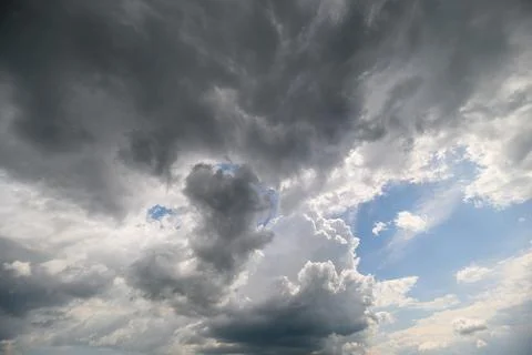A captivating view of dark clouds contrasting with a bright blue sky, radiati 写真素材
