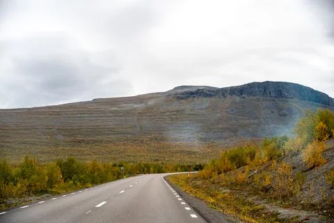 A captivating view of a desolate yet beautiful winding asphalt road, stretchi Stock Photos