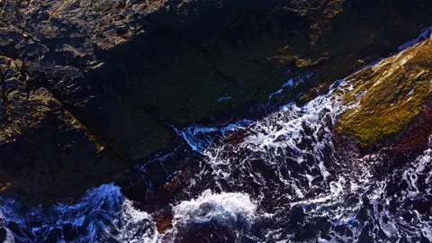 Captivating waves crash against rugged rocks at sunrise along the tranquil Stock Footage 335422069
