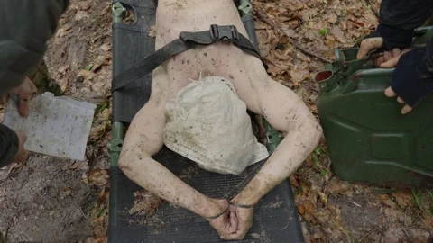 Captive With Head Covered In Sack Shivering While Lying On Stretcher During Video stock 328951330