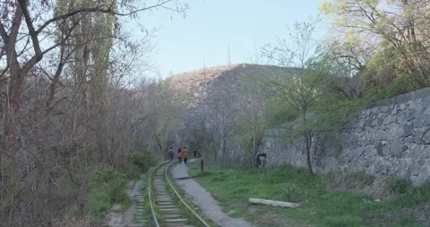 Capture a group of people exploring an abandoned railway along a rocky path with Видео 252467053
