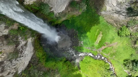Captured mid plunge, the roaring column of water crashes into a rocky bowl Video stock 328222804