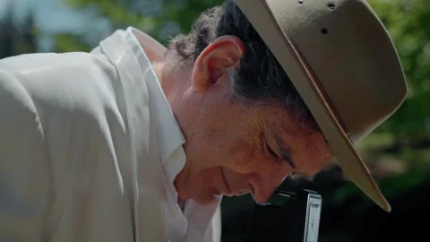 Capturing moments with an analog camera in nature by a man wearing a fedora Stock Footage 321370222